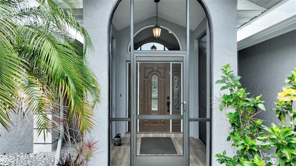The exterior entrance features a screened arched doorway leading to a wood-paneled front door — 25101 KIMBERLY COURT, PUNTA GORDA, FL