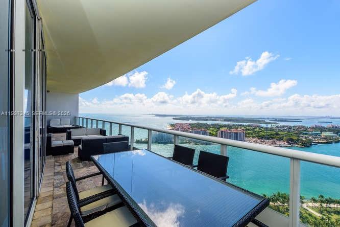 A high-rise balcony features outdoor dining furniture and lounge seating overlooking a coastal bay view — 100 S Pointe Dr # 3101, Miami Beach FL 33139, MIAMI BEACH, FL