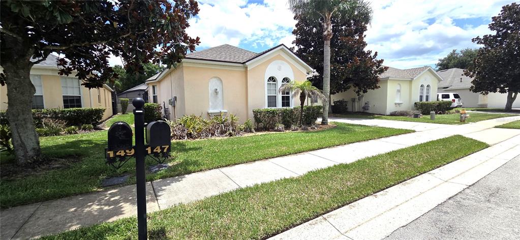 The exterior of two adjacent single-story stucco houses with a shared mailbox post in front — 147 MINNIEHAHA CIRCLE, HAINES CITY, FL
