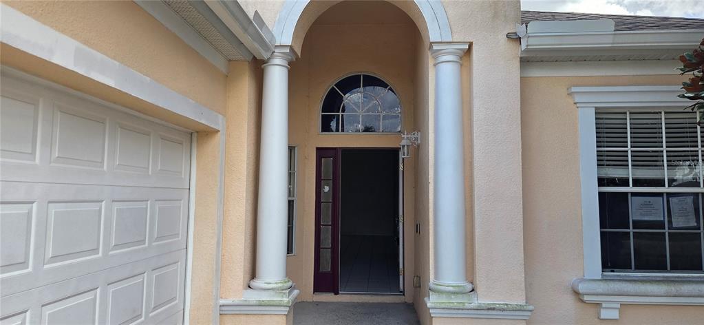 The exterior of a house features a covered entryway with two white columns and a door — 147 MINNIEHAHA CIRCLE, HAINES CITY, FL