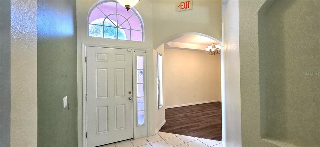 An entryway features a white front door, arched transom window, tile flooring, and an exit sign — 147 MINNIEHAHA CIRCLE, HAINES CITY, FL