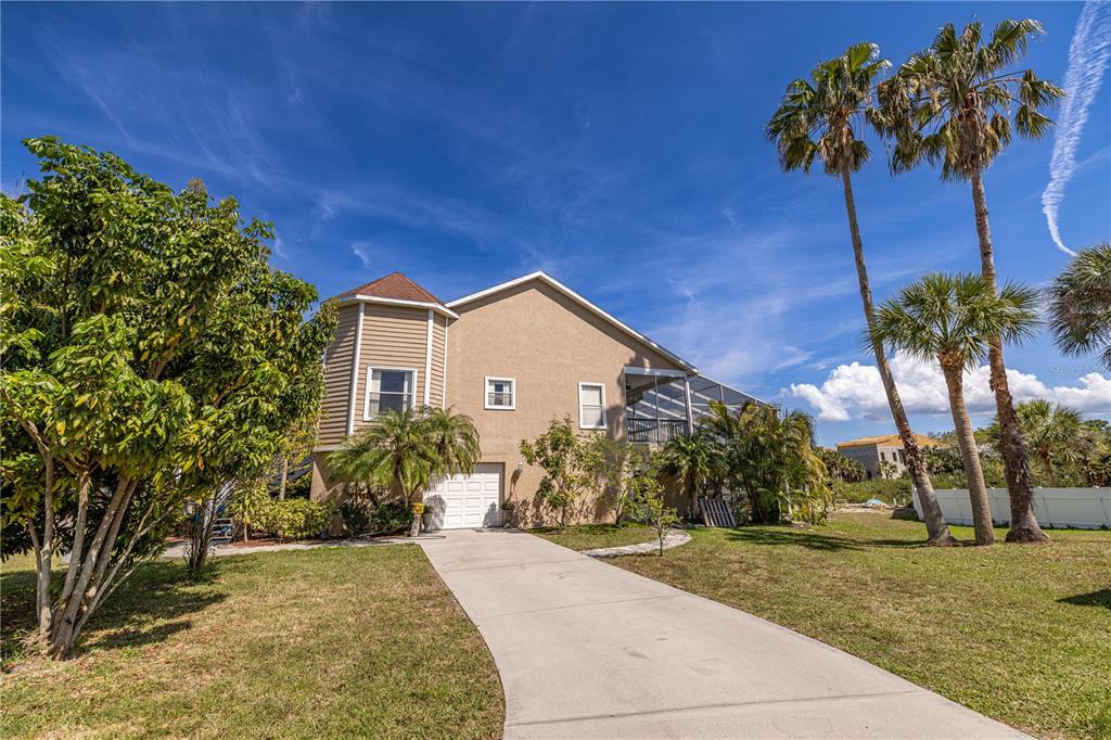 A two-story house with a beige exterior, a concrete driveway, and palm trees in front — 7345 BRIGHTWATERS COURT, NEW PORT RICHEY, FL