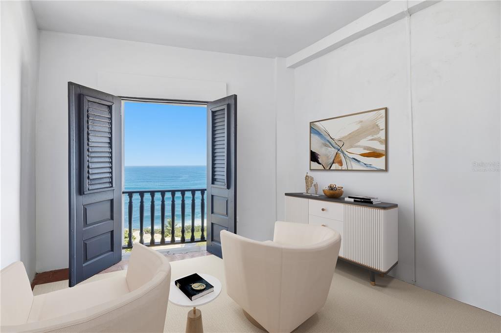 A room with two cream chairs, a white sideboard, and open doors revealing an ocean view — 418-419 NORZAGARAY AND SOL STREETS, SAN JUAN, PR