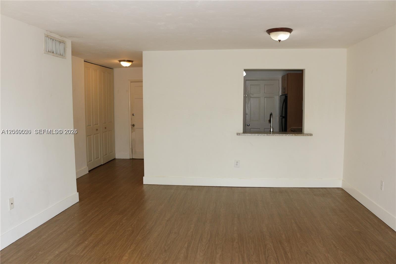 This room features wood-look flooring, white walls, a pass-through window to the kitchen, and closets — 9611 SW 77th Ave # 306A, Miami FL 33156, MIAMI, FL