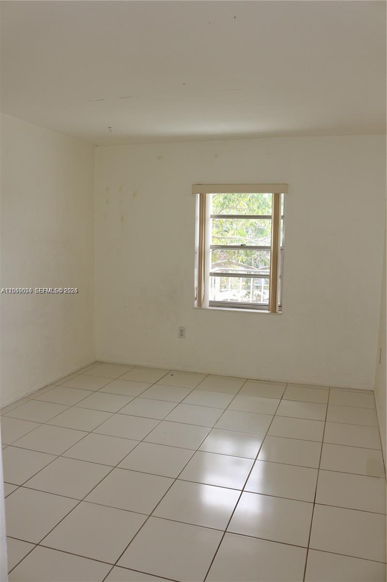 An empty room features white walls, light-colored floor tiles, and a single window — 9611 SW 77th Ave # 306A, Miami FL 33156, MIAMI, FL
