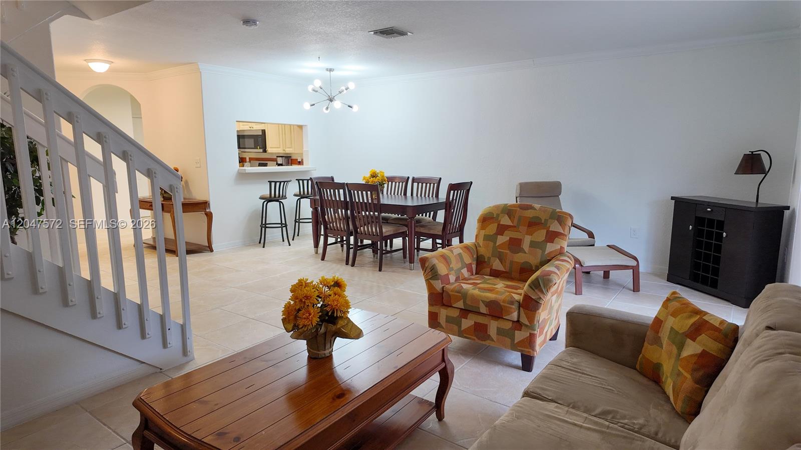 An open-concept living and dining area features tile flooring, a wooden coffee table, and stairs — 11432 NW 48th Ter, Doral FL 33178, DORAL, FL