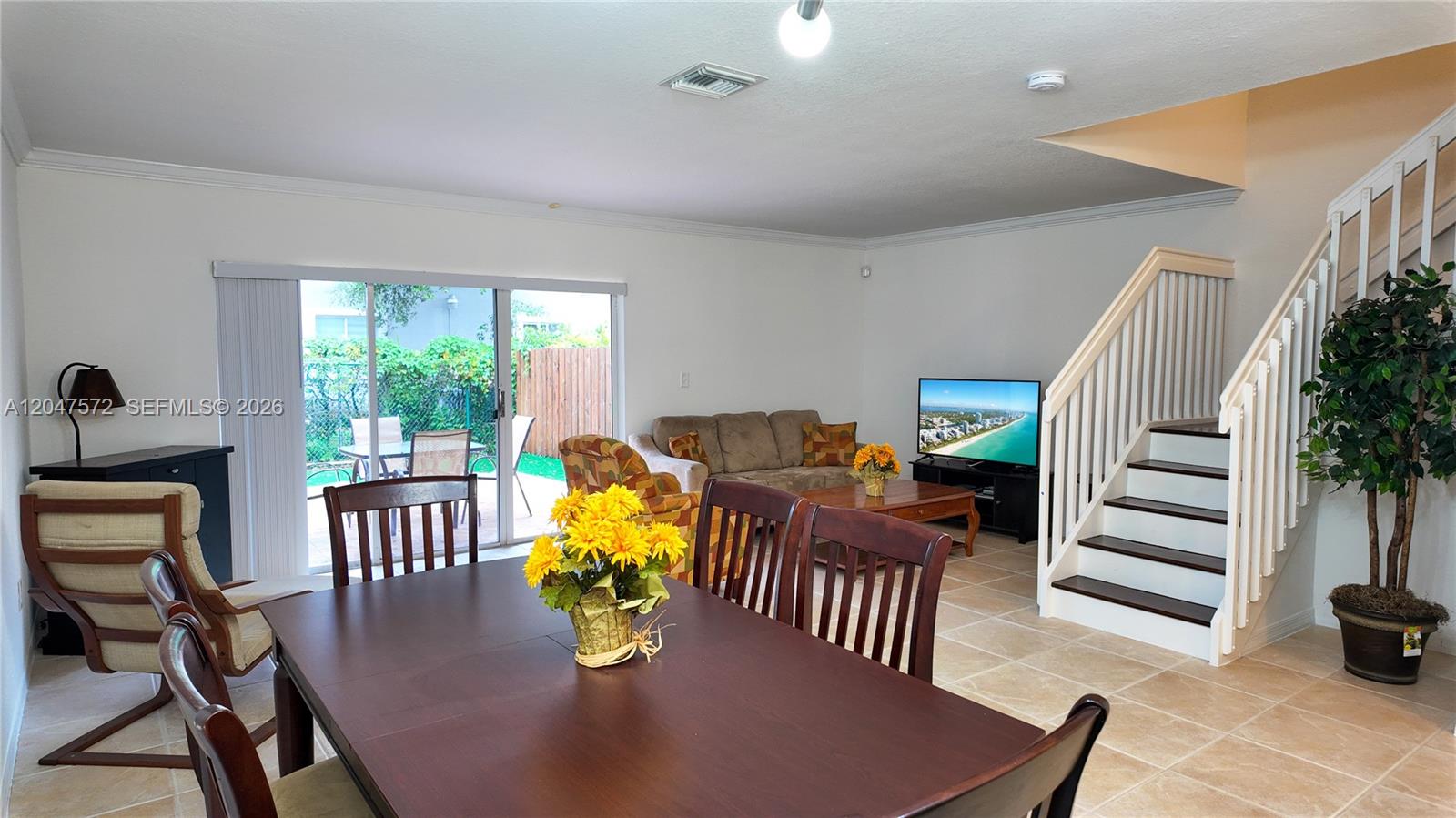 A dining area with a wooden table leads into a living room with stairs — 11432 NW 48th Ter, Doral FL 33178, DORAL, FL
