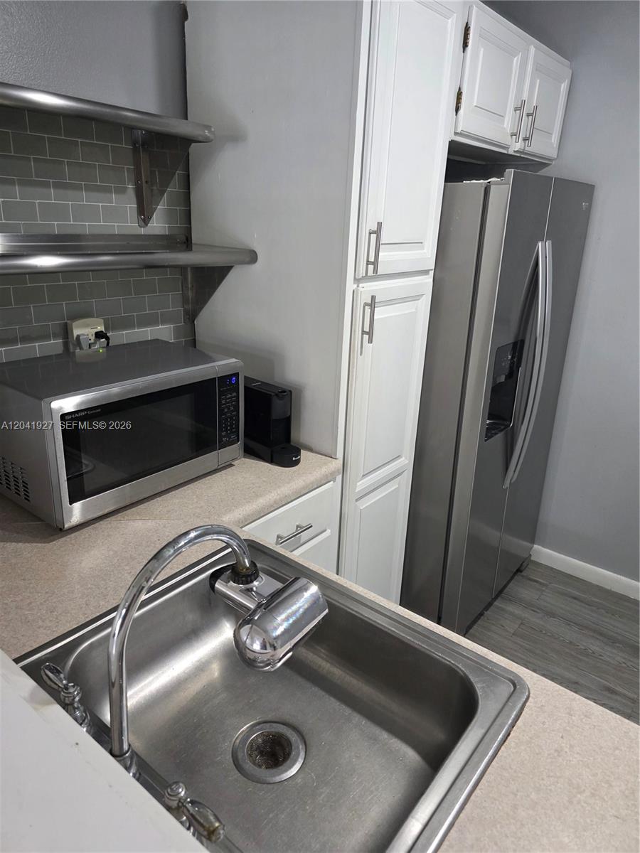 A kitchen features a stainless steel sink, a microwave, open shelving, and a refrigerator — 8065 SW 107th Ave # 202, Miami FL 33173, MIAMI, FL