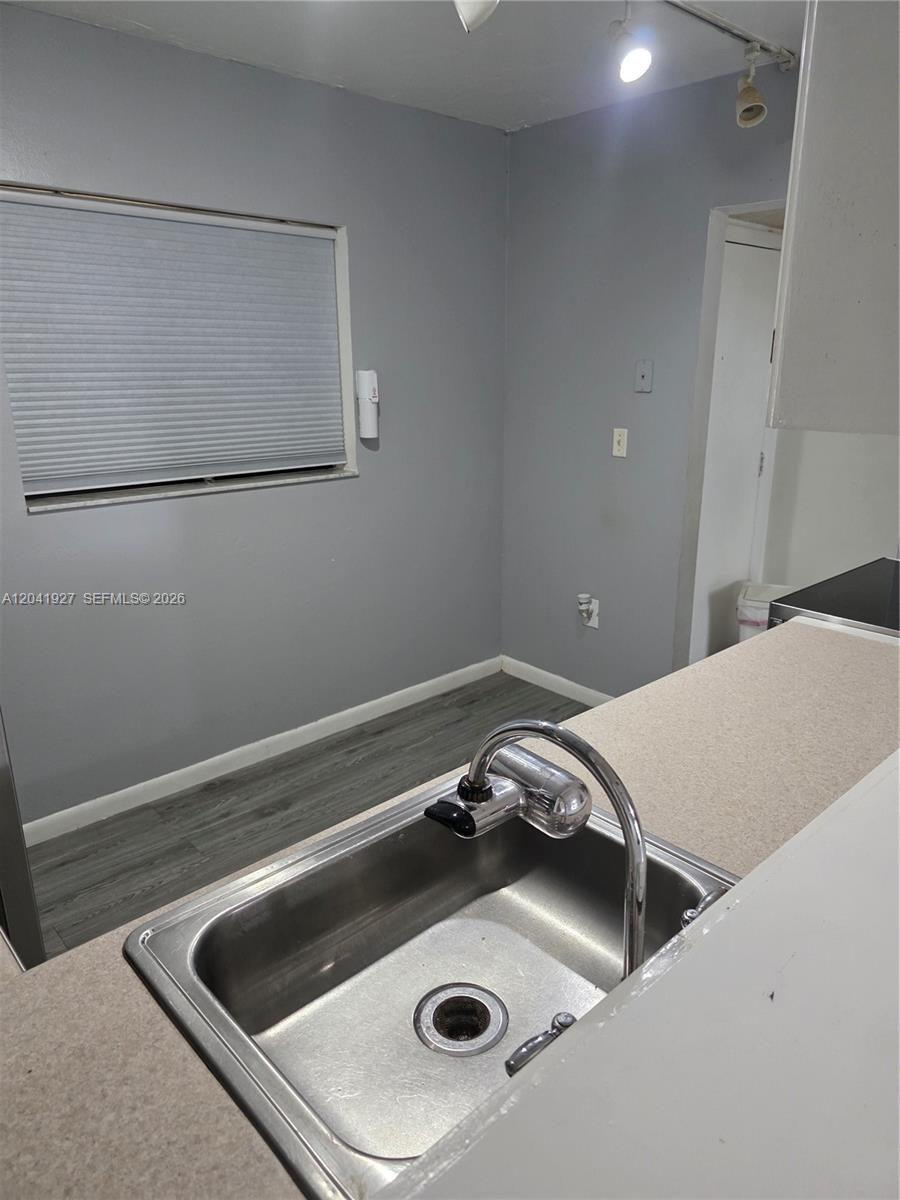 A kitchen sink with a chrome faucet sits in front of a gray-walled room — 8065 SW 107th Ave # 202, Miami FL 33173, MIAMI, FL