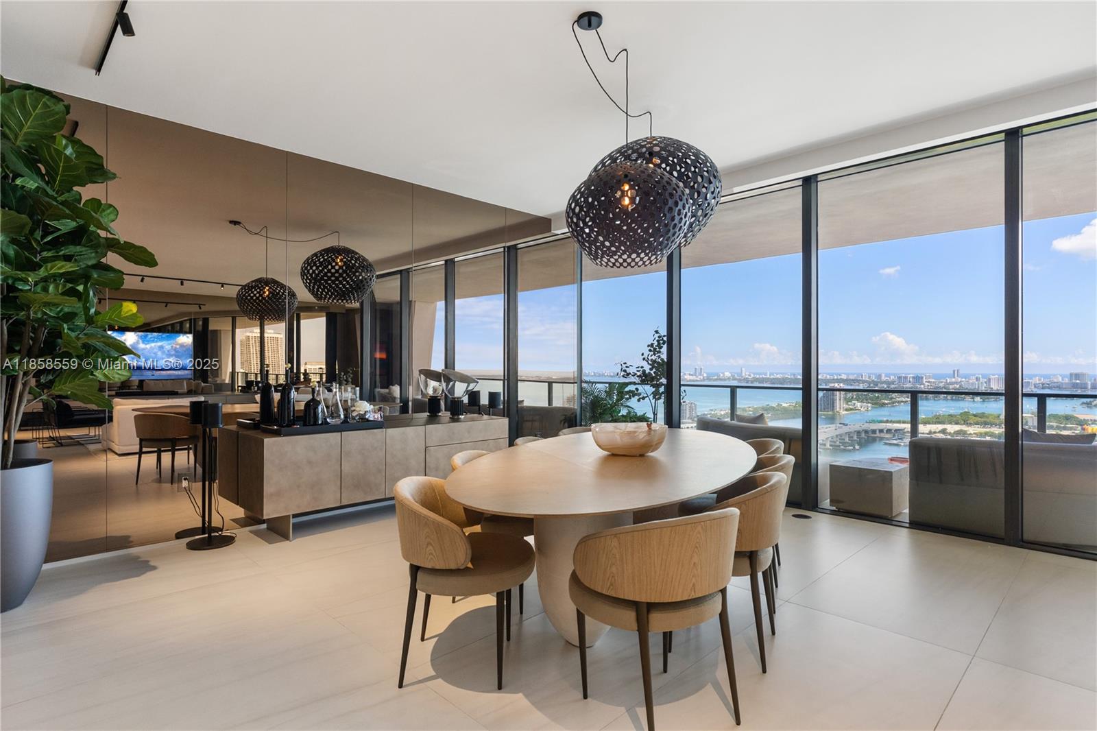 A modern dining room features an oval table, pendant lights, and floor-to-ceiling windows with views — 1000 Biscayne Blvd # 3502, Miami FL 33132, MIAMI, FL