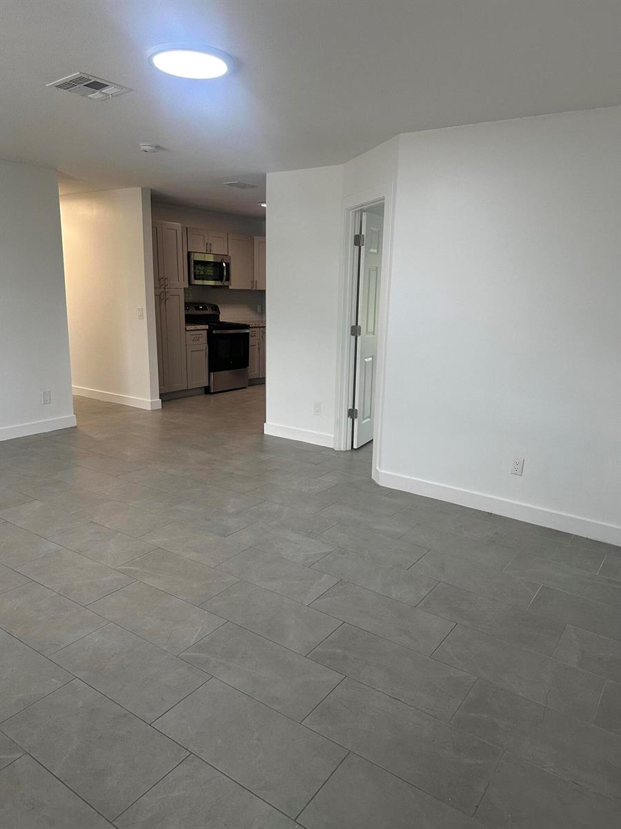 A view of a kitchen with stainless steel appliances from a tiled living area — 4786 Cambridge Street, FL 33463, FL