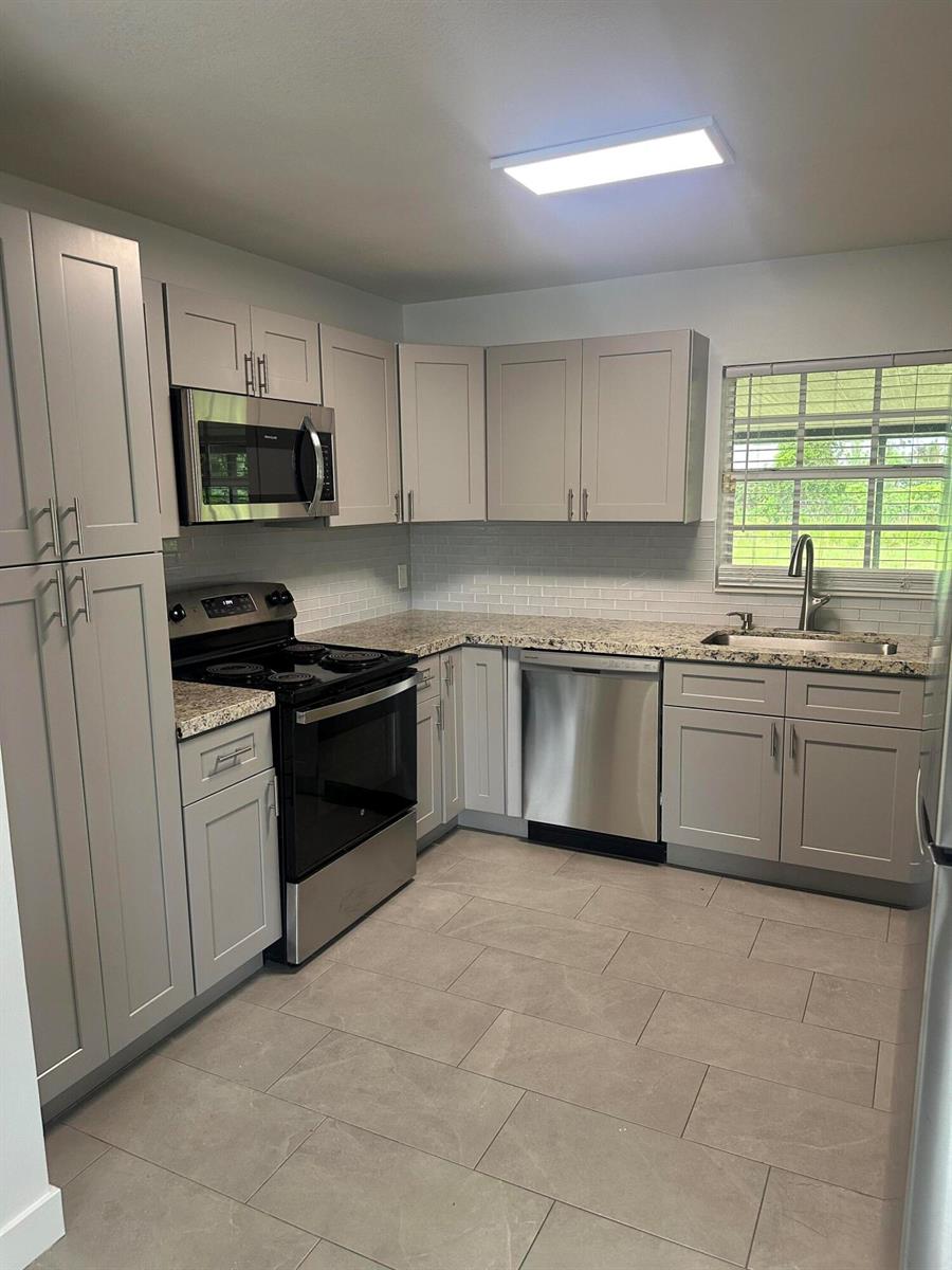 A kitchen with light gray cabinets, stainless steel appliances, granite countertops, and tile flooring — 4786 Cambridge Street, FL 33463, FL