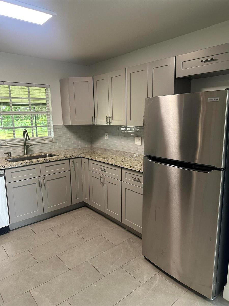 A kitchen features gray cabinets, granite countertops, a subway tile backsplash, and stainless steel appliances — 4786 Cambridge Street, FL 33463, FL