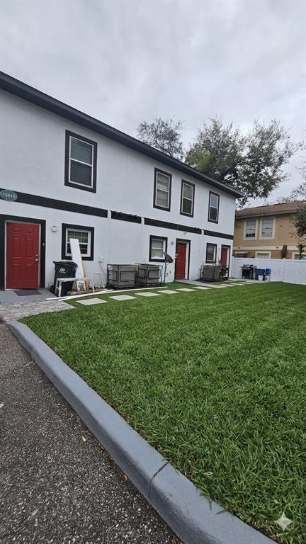 A two-story white building with red doors and a green lawn in front — 13612 N 21ST STREET, TAMPA, FL