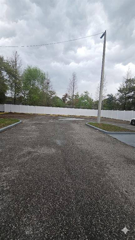An outdoor parking lot with a white vinyl fence and a tall utility pole — 13612 N 21ST STREET, TAMPA, FL