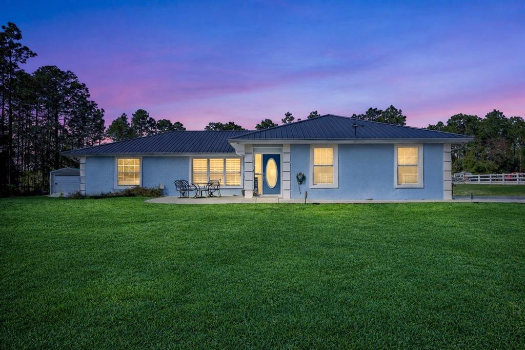 A blue single-story house with a metal roof stands behind a large green lawn — 11920 SW 45TH STREET, OCALA, FL