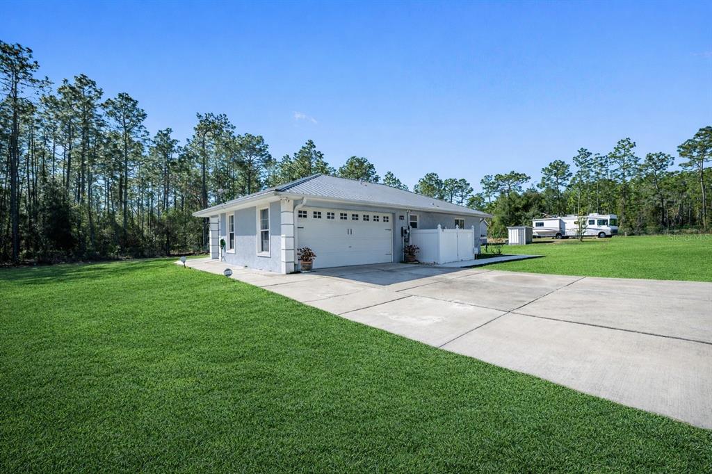A light-colored house with a metal roof and a concrete driveway sits on a lawn — 11920 SW 45TH STREET, OCALA, FL