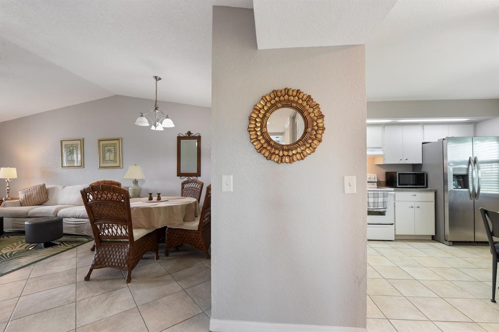A central wall with a round mirror separates a dining area from a kitchen — 449 ROYAL POINCIANA UNIT 221, PUNTA GORDA, FL