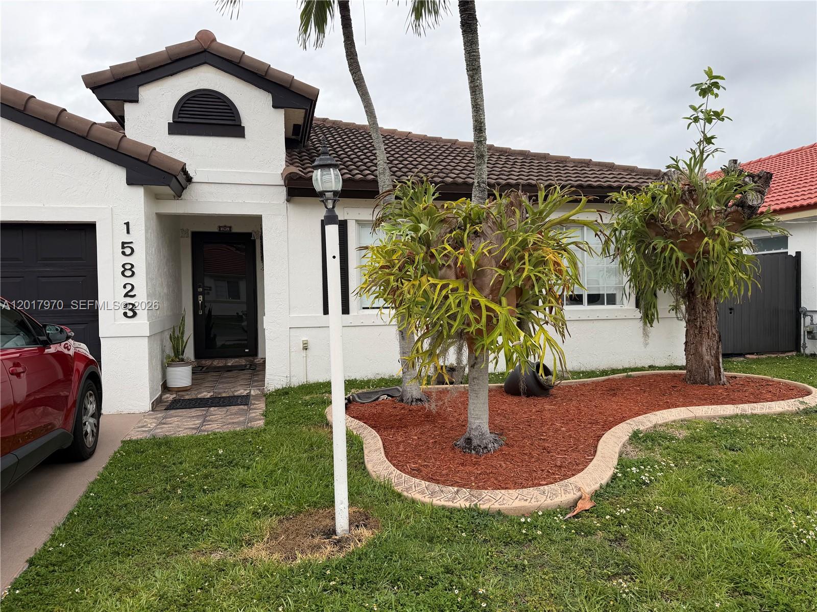 A single-story house with a white stucco facade, brown tile roof, and two large staghorn ferns — 15823 SW 82nd St, Miami FL 33193, MIAMI, FL