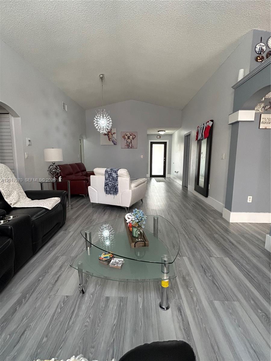 A living room features gray wood-look flooring, a glass coffee table, and multiple sofas — 15823 SW 82nd St, Miami FL 33193, MIAMI, FL