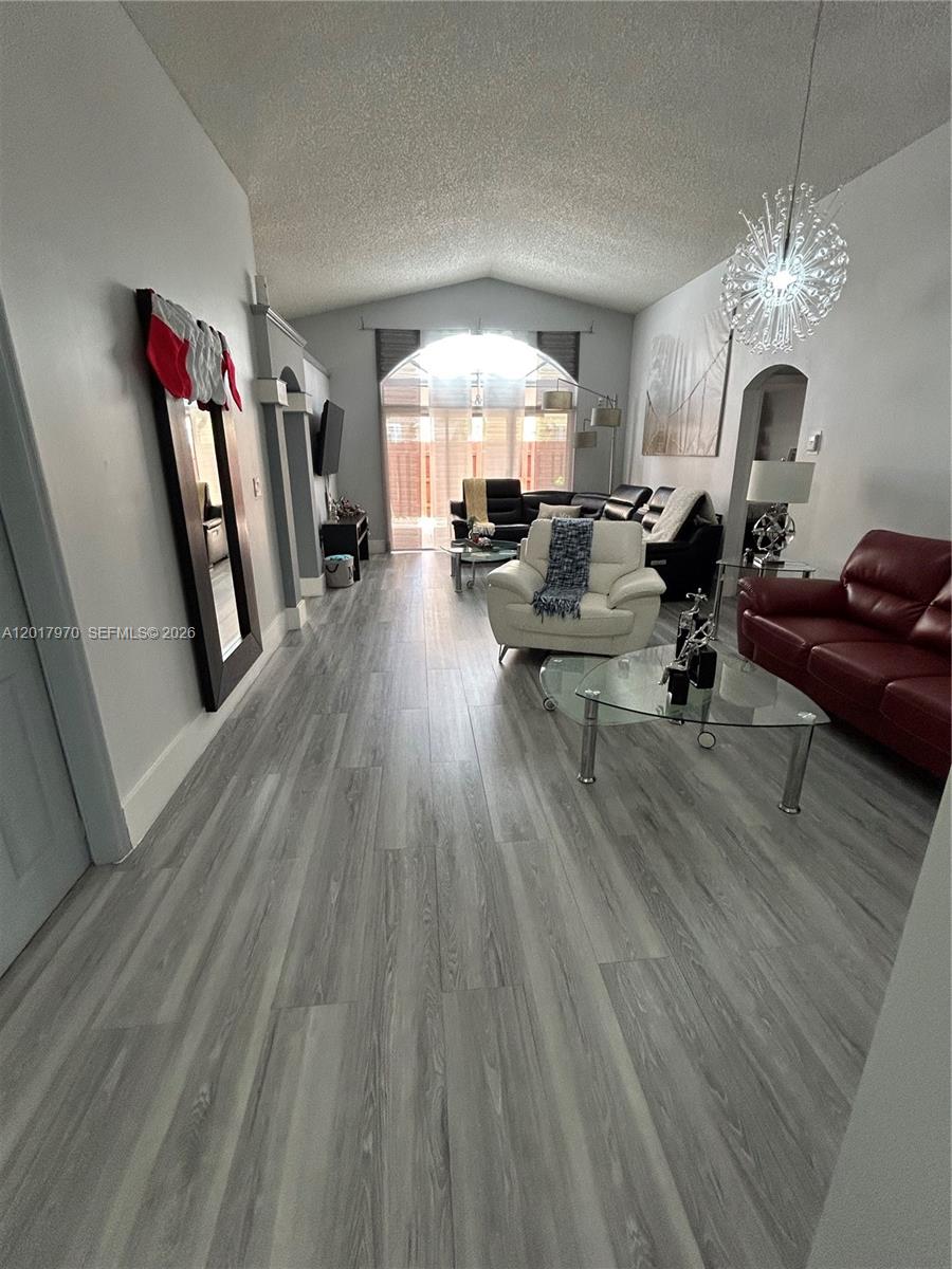 A living room features vaulted ceilings, gray wood-look flooring, and a mix of seating furniture — 15823 SW 82nd St, Miami FL 33193, MIAMI, FL