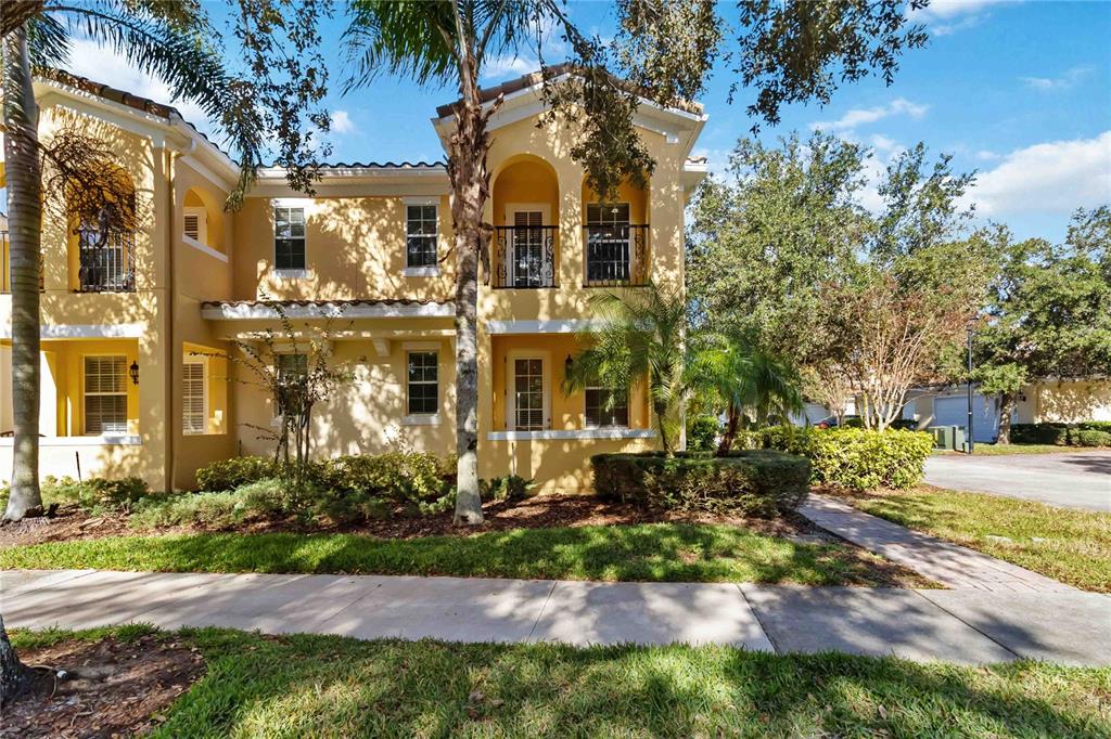 A two-story yellow stucco townhouse with arched balconies and a palm tree in the front — 8681 LOWER VILLAGEWALK CIRCLE, ORLANDO, FL