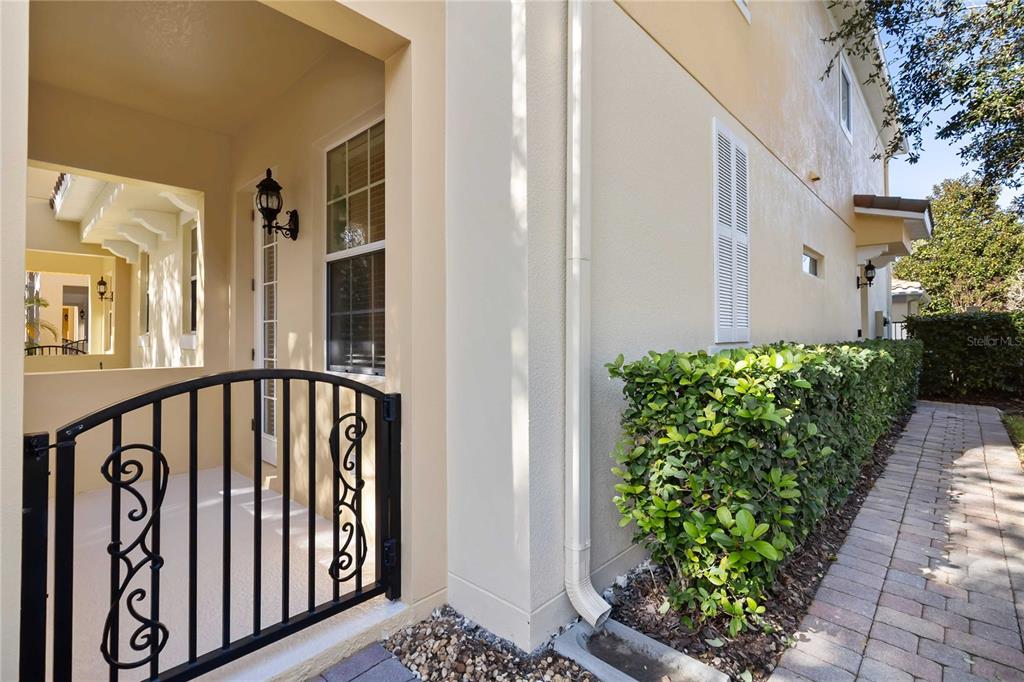 A two-story yellow stucco townhouse with arched balconies and a paved walkway — 8681 LOWER VILLAGEWALK CIRCLE, ORLANDO, FL