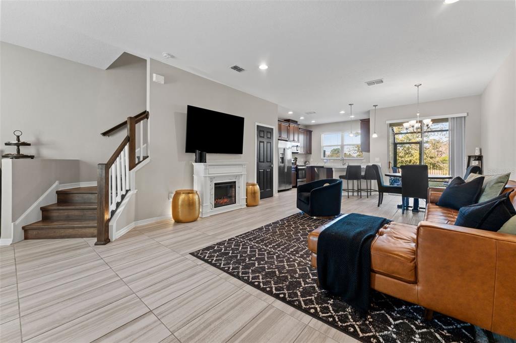 An open-concept living room and kitchen featuring tile flooring, a fireplace, and a staircase — 29913 SOUTHWELL LANE, WESLEY CHAPEL, FL