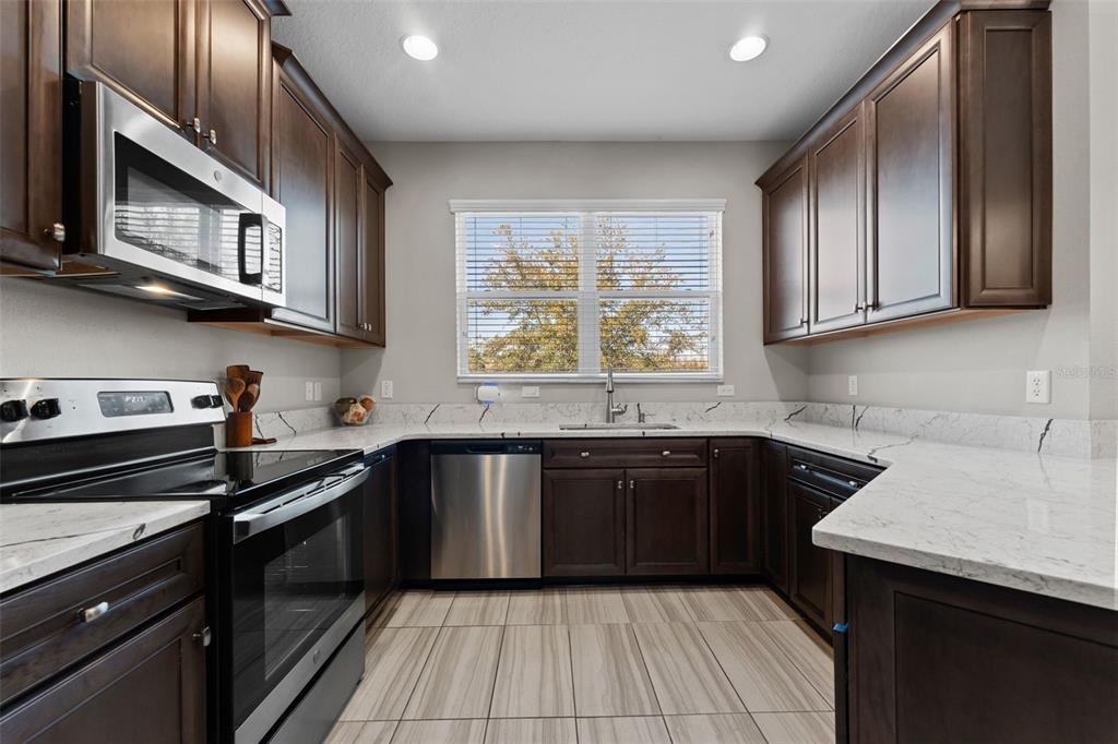 A kitchen features dark wood cabinets, stainless steel appliances, and white marble-patterned countertops — 29913 SOUTHWELL LANE, WESLEY CHAPEL, FL