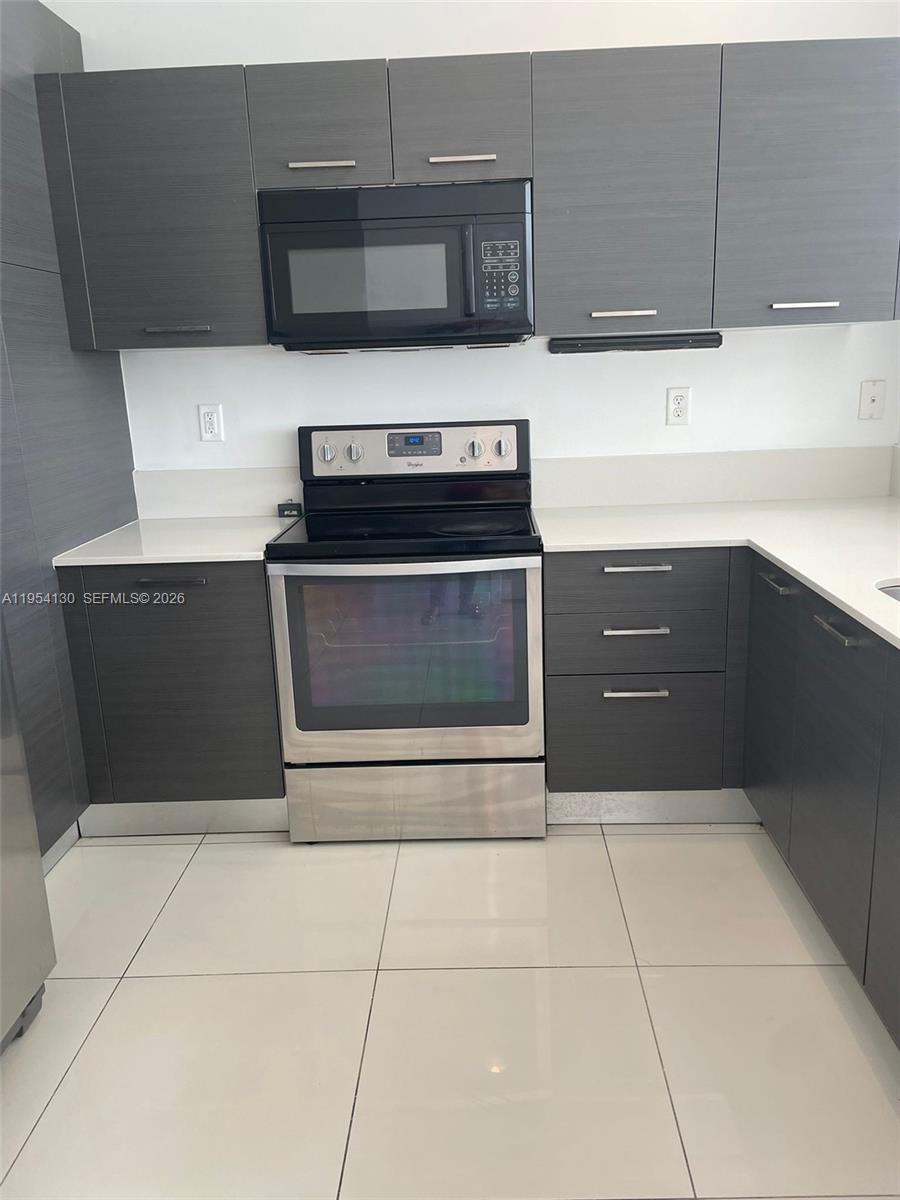A kitchen features dark gray flat-panel cabinets, stainless steel appliances, and white countertops — 3486 NW 13th St # 3486, Lauderhill FL 33311, LAUDERHILL, FL