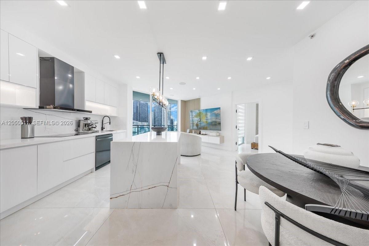 A modern white kitchen features a marble island, sleek cabinetry, and an open living area — 350 S Miami Ave # 2314, Miami FL 33130, MIAMI, FL