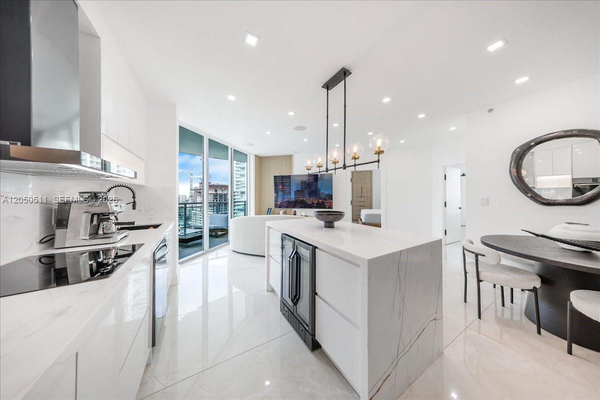 A modern kitchen features white marble countertops, a central island, and an adjacent dining area — 350 S Miami Ave # 2314, Miami FL 33130, MIAMI, FL