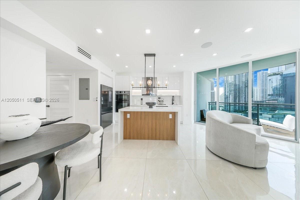 A modern kitchen and living area feature a wood-paneled island, white cabinetry, and balcony views — 350 S Miami Ave # 2314, Miami FL 33130, MIAMI, FL