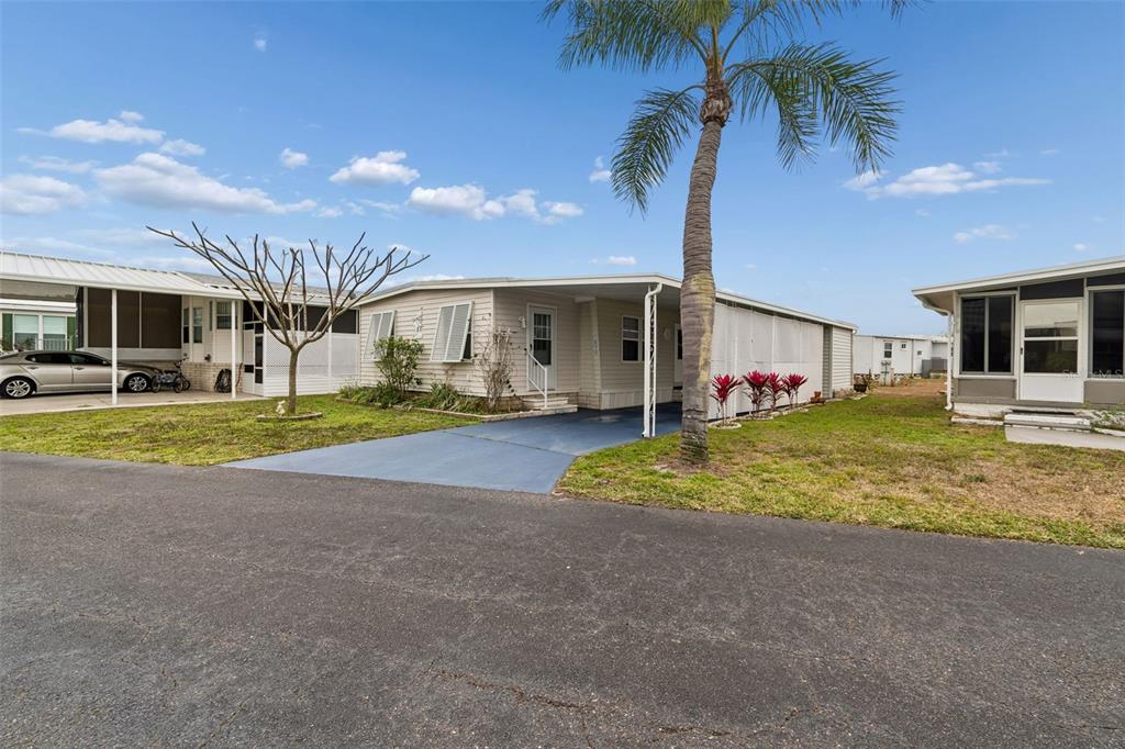 A single-story manufactured home with a blue driveway and a palm tree in the yard — 678 MOUNT MADISON AVENUE NE UNIT 661, ST PETERSBURG, FL