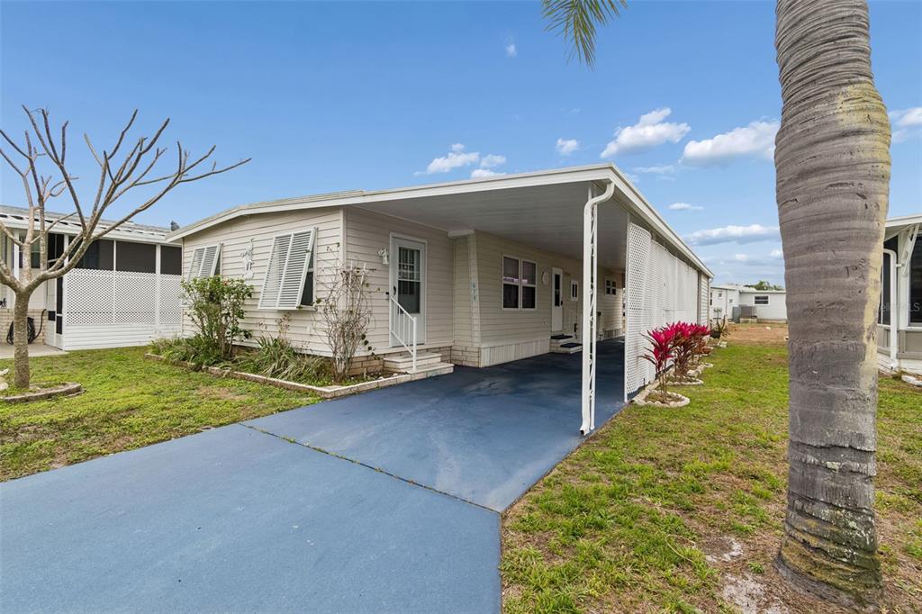 A single-story manufactured home with a blue driveway, a carport, and a palm tree — 678 MOUNT MADISON AVENUE NE UNIT 661, ST PETERSBURG, FL