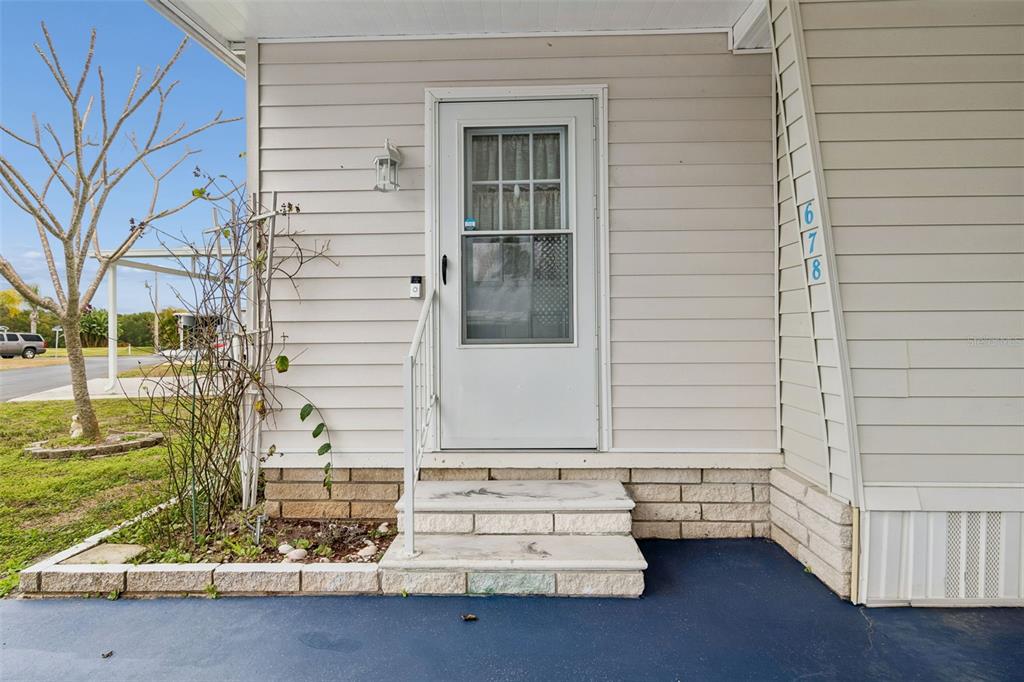 A light-colored house exterior features a white front door, two stone steps, and house numbers — 678 MOUNT MADISON AVENUE NE UNIT 661, ST PETERSBURG, FL