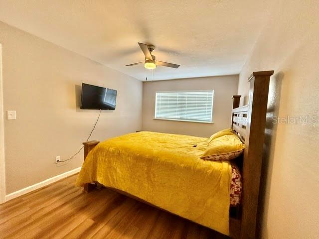 A bedroom with a yellow bedspread, a ceiling fan, and a wall-mounted television — 265 W TOWNE PLACE, TITUSVILLE, FL