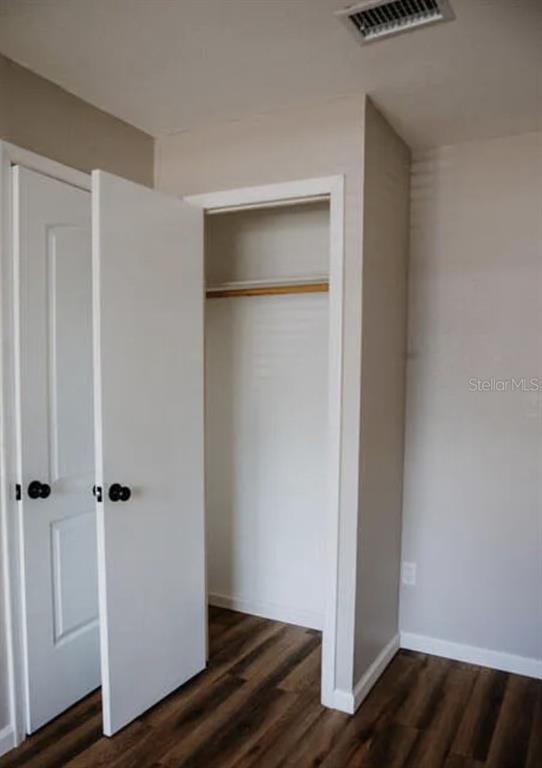 A room with wood-look flooring, a white door, and an open closet with a hanging rod — 265 W TOWNE PLACE, TITUSVILLE, FL