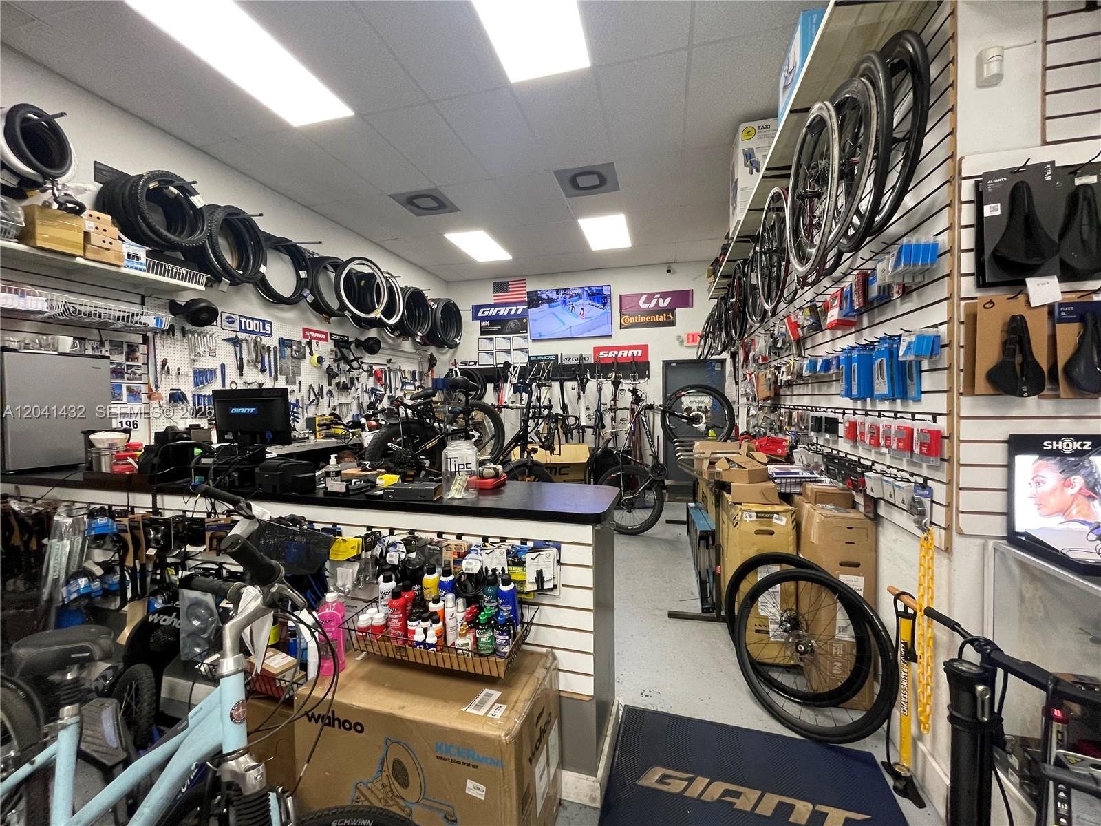 A bicycle shop interior features rows of hanging tires, wheels, bike parts, and service equipment — 14097 SW 88th St, Miami FL 33186, MIAMI, FL