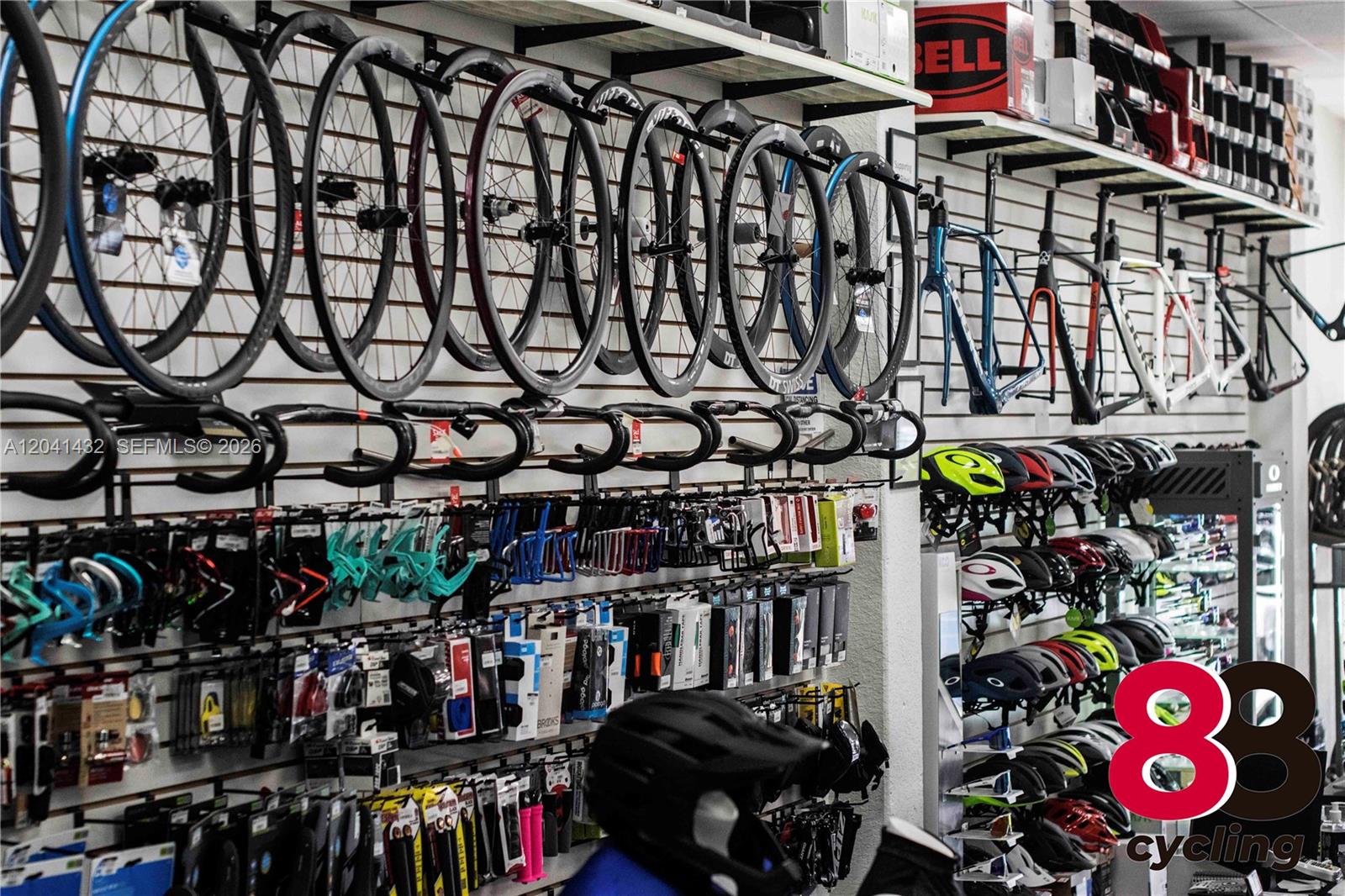 A retail bike shop displays bicycle wheels, frames, handlebars, and helmets on wall-mounted racks — 14097 SW 88th St, Miami FL 33186, MIAMI, FL