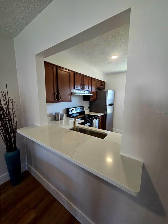 A kitchen with wood cabinets, stainless steel appliances, and a white quartz breakfast bar — 13719 MISSION OAKS BOULEVARD UNIT 0, SEMINOLE, FL