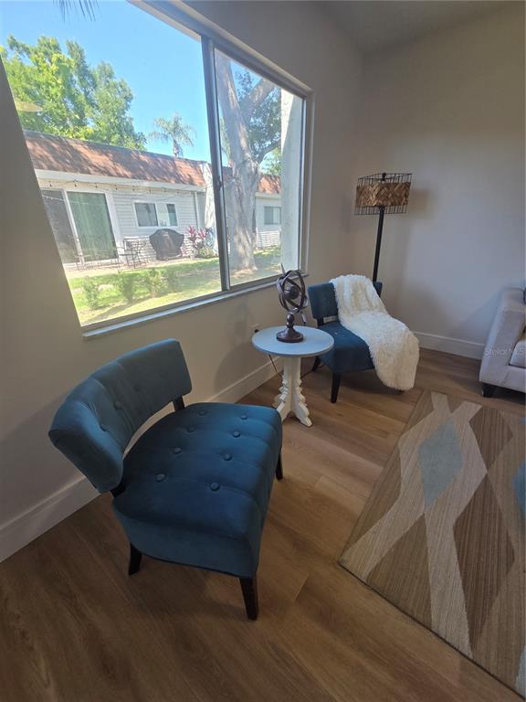 A living area features two blue tufted chairs, a small round table, and a large window — 13719 MISSION OAKS BOULEVARD UNIT 0, SEMINOLE, FL