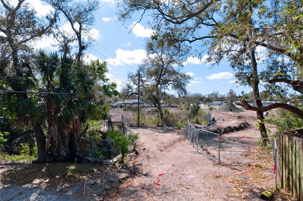 A dirt path leads through a chain-link fence into a cleared, undeveloped lot with trees — 4101 S SCHOOL AVENUE, SARASOTA, FL