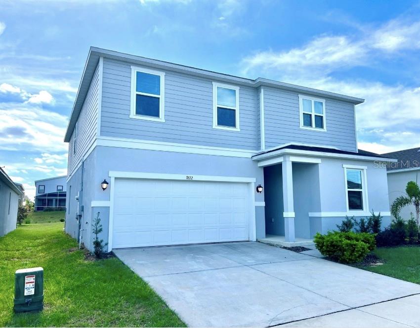 A two-story house with light blue siding, a two-car garage, and a concrete driveway — 9112 WESTSIDE HILLS DRIVE, DAVENPORT, FL