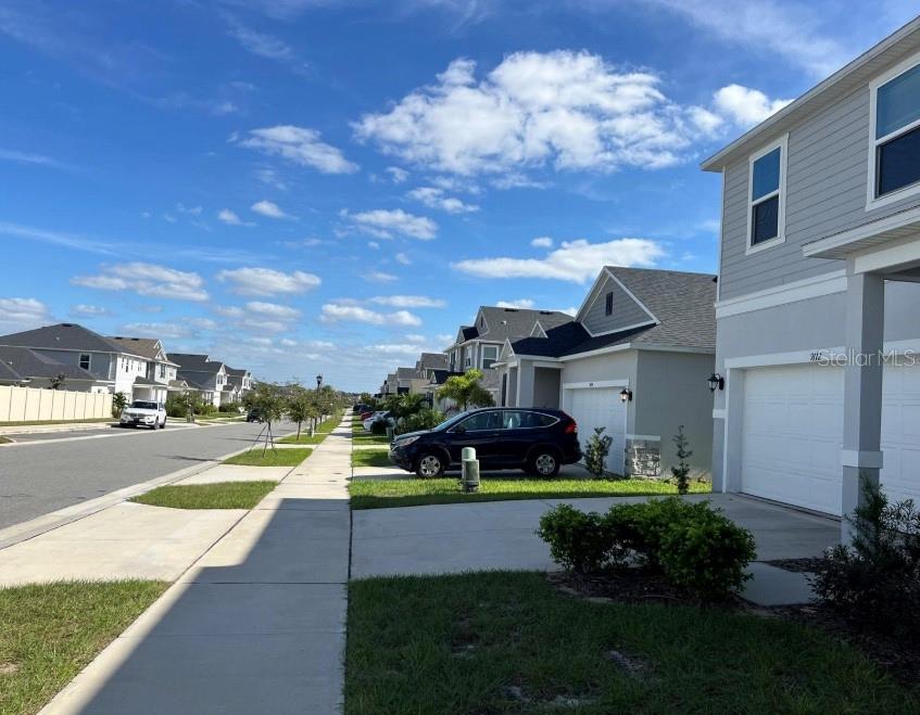 A suburban street view showing residential houses with driveways and a parked SUV — 9112 WESTSIDE HILLS DRIVE, DAVENPORT, FL