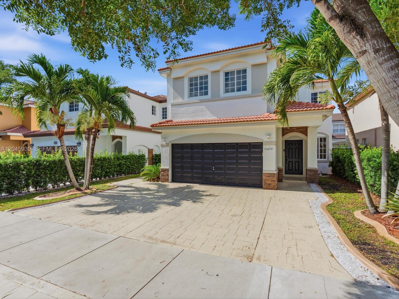 A two-story suburban house with a paved driveway, a dark garage door, and palm trees — 11274 NW 43rd Ter # 0, Doral FL 33178, DORAL, FL