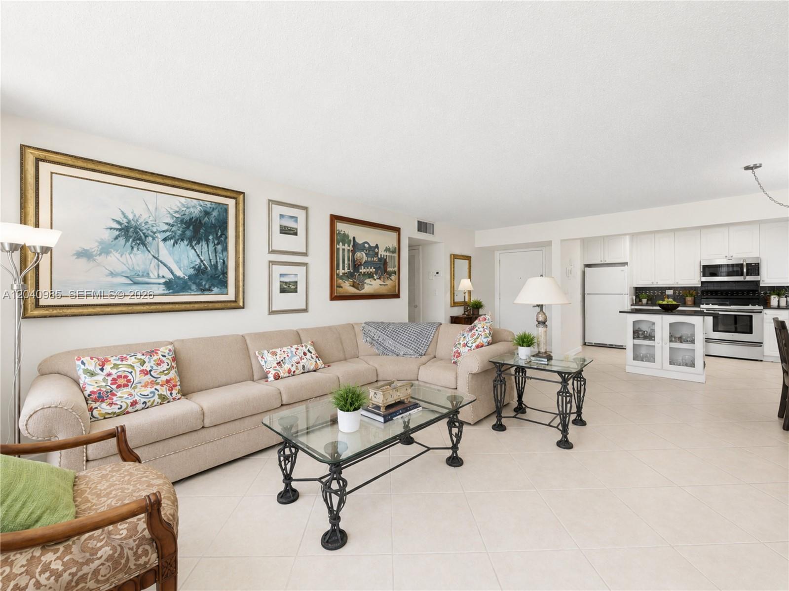 A living room with a beige sectional sofa, glass coffee table, and an open kitchen — 1817 S Ocean Dr # 620, Hallandale Beach FL 33009, HALLANDALE BEACH, FL