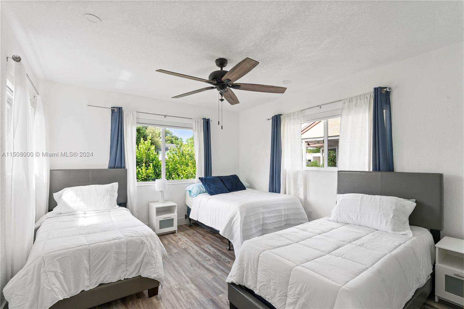 A bedroom features three beds, white walls, wood-look flooring, and a ceiling fan — 236 NW 42nd St, Miami FL 33127, MIAMI, FL