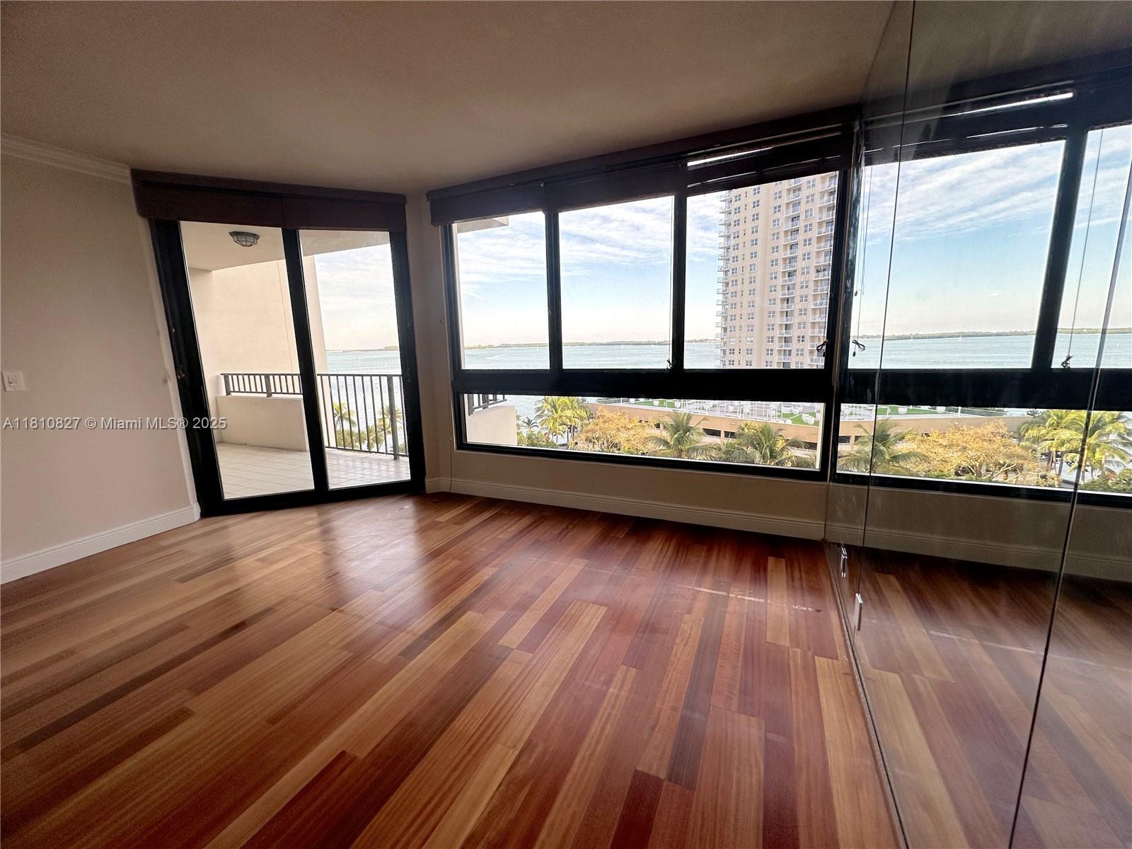 An empty room with hardwood floors, floor-to-ceiling windows, and a balcony overlooking the water — 520 Brickell Key Dr # A811, Miami FL 33131, MIAMI, FL