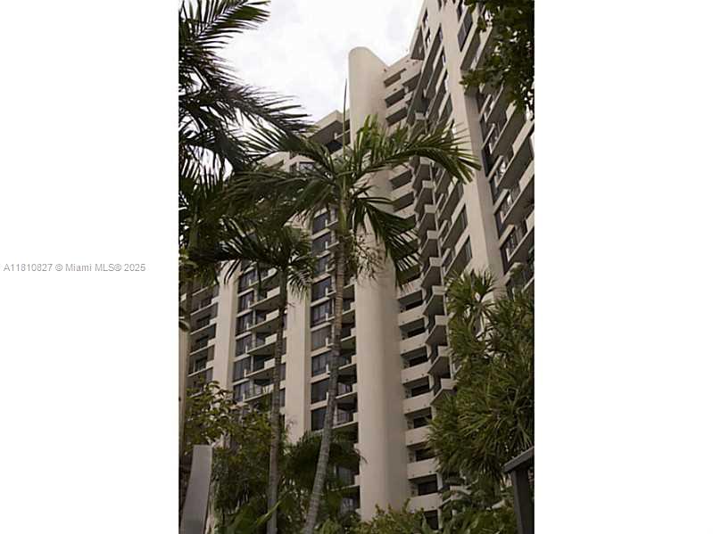A tall, multi-story residential building is framed by palm trees against a cloudy sky — 520 Brickell Key Dr # A811, Miami FL 33131, MIAMI, FL